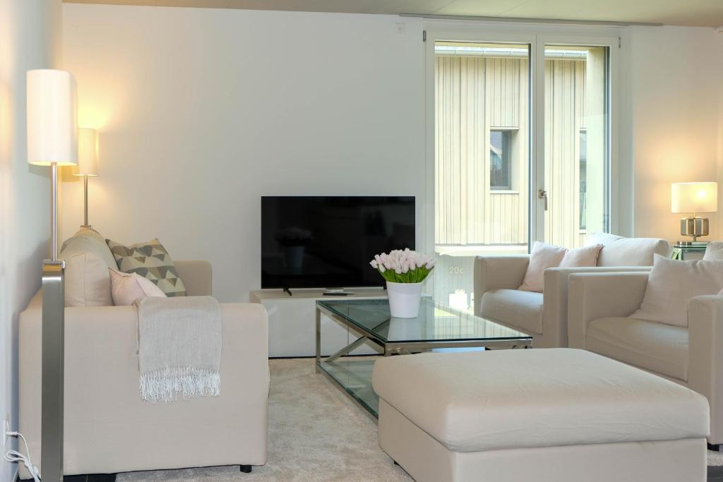 a living room with white furniture and a tv at Schlossblick in Spiez