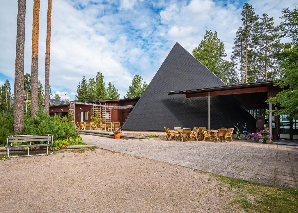 a building with a triangular roof with tables and chairs at Honkiniemi in Ähtäri