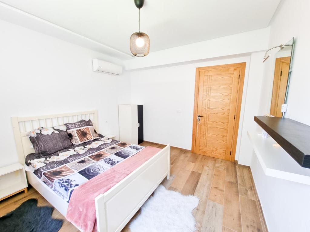 a white bedroom with a bed and a wooden floor at Appartement Salon et une chambre - TUN104 in Nabeul