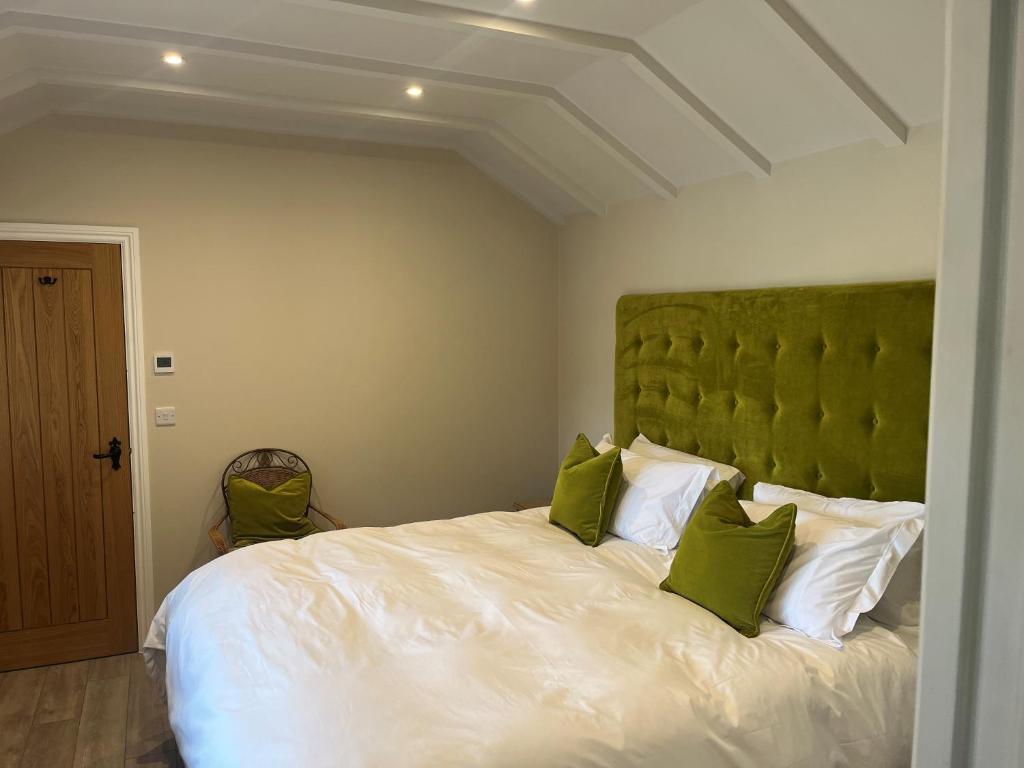 um quarto com uma grande cama branca com almofadas verdes em The Retreat Field View em Great Maplestead