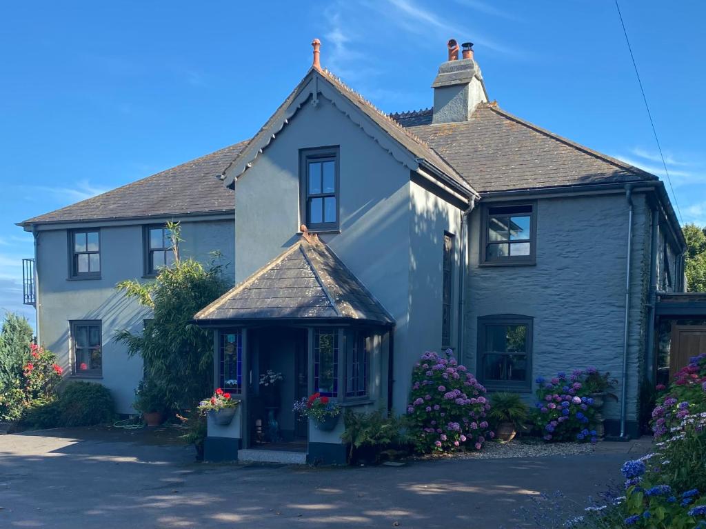 a white house with flowers in the front yard at Downton Lodge Country Bed and Breakfast and; Self Catering in Dartmouth