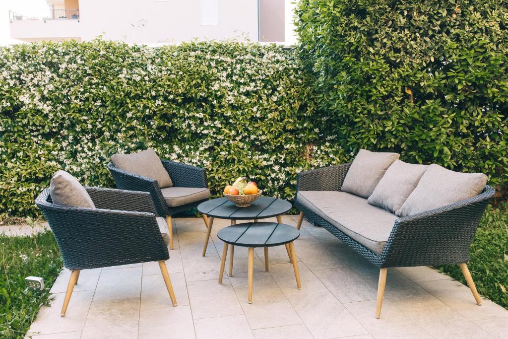 een patio met 3 stoelen, een tafel en een heg bij Edonia Garden Home Comfortable & stylish duplex apartment with relaxing private garden in Brodarica