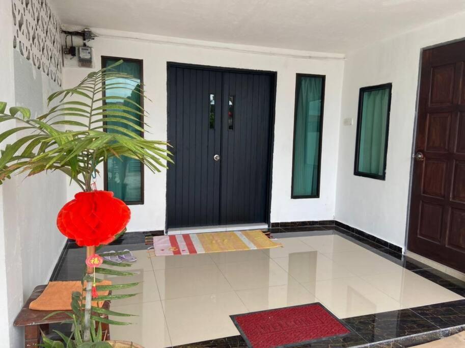 een hal met een zwarte deur en een plant bij Homestay Taman Sri Nibong 庆丰园 in Nibung Tebal