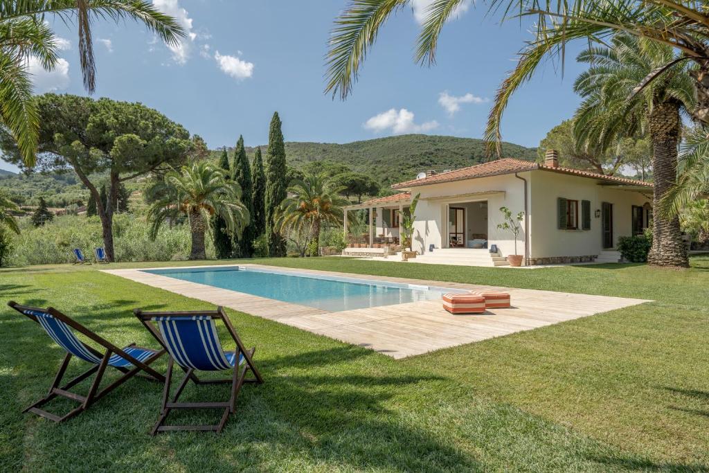 カポリーヴェリにあるVilla Elle Exclusive Isola d'Elbaの中庭にプールと椅子2脚が備わる家