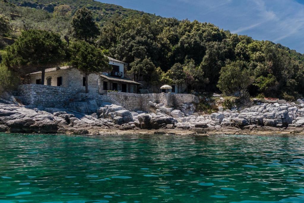 a house on a rocky shore next to the water at Big Blue Pelion in Pilion