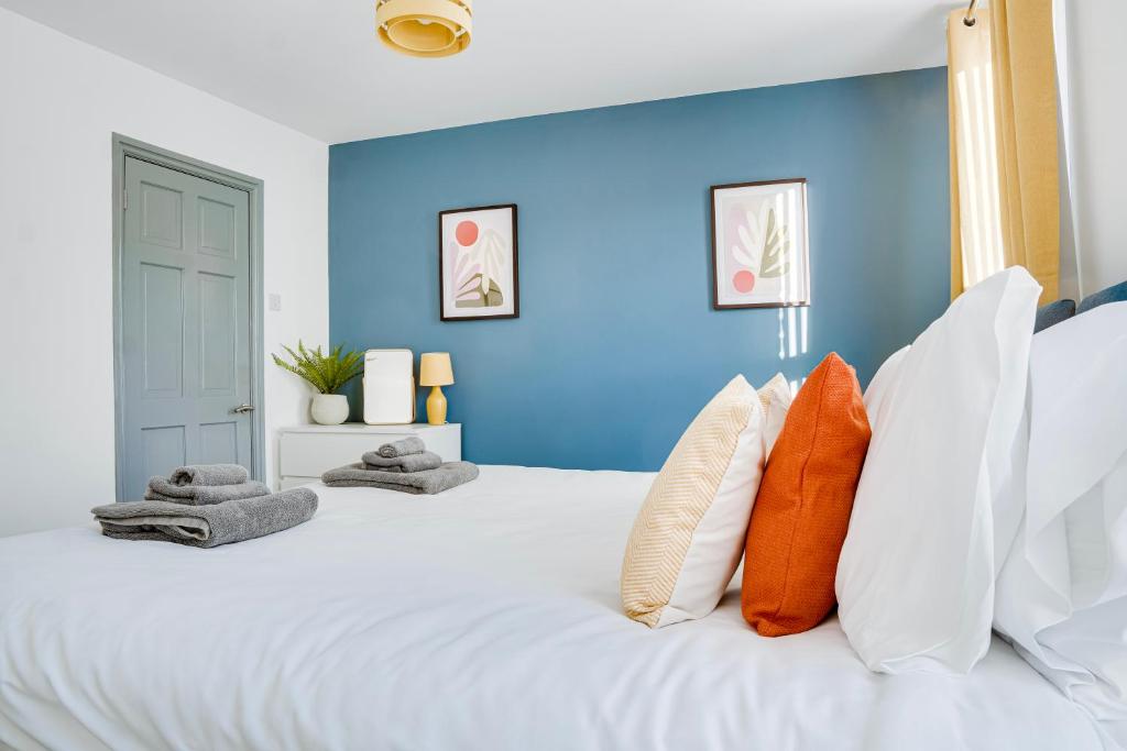 a blue bedroom with a large white bed with orange pillows at Cosy 3 bedroom house near Anfield Stadium in Liverpool