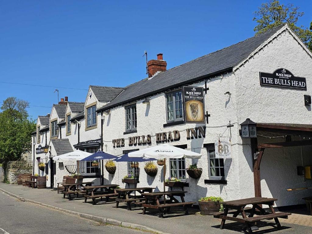 a pub with tables and umbrellas on a street at The Bull at Foolow in Hucklow