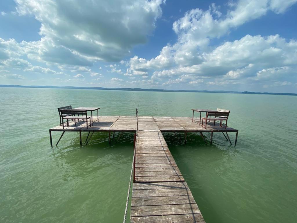 two benches sitting on a dock in the water at Tóparti Apartmanház in Balatonszárszó