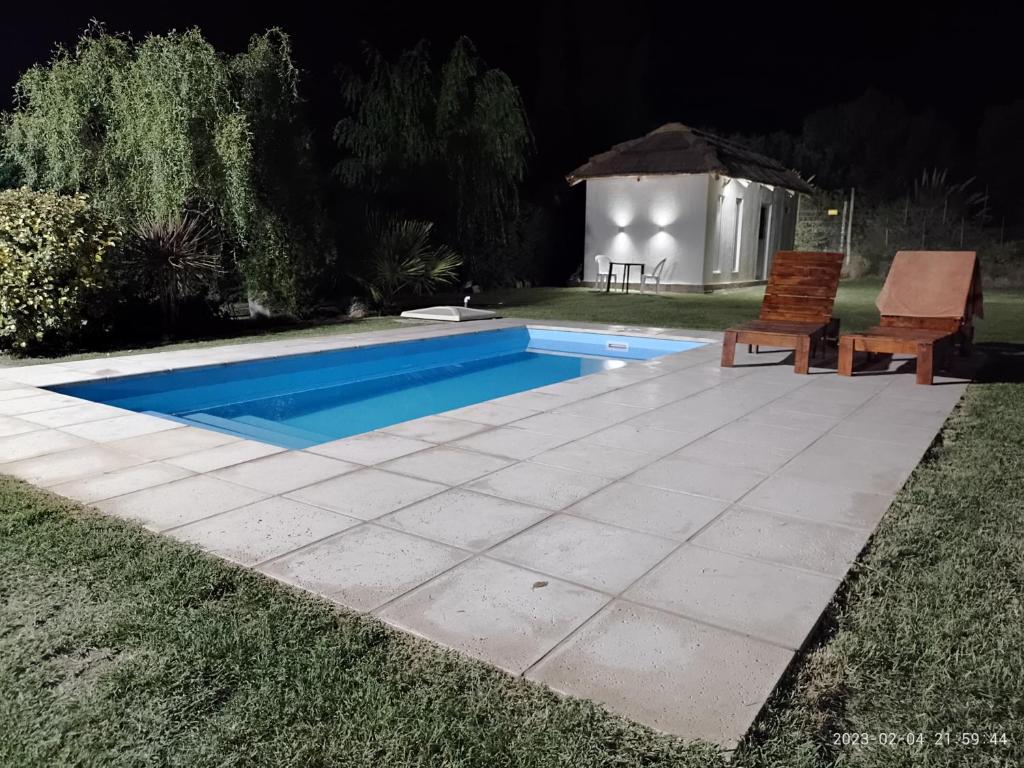 una piscina por la noche con 2 sillas y un cenador en La Cabaña de Eco Verde en San Rafael