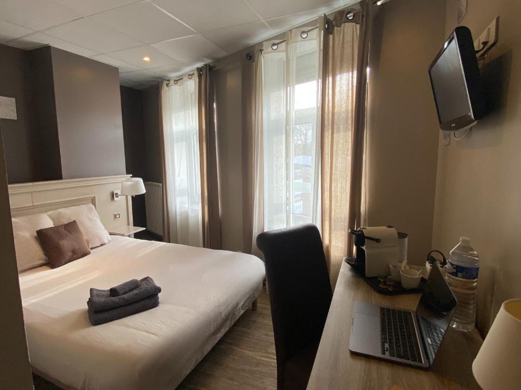 ein Hotelzimmer mit einem Bett und einem Laptop auf dem Schreibtisch in der Unterkunft La Pause Voyage in Bourbourg