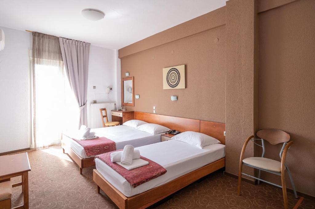 a hotel room with two beds and a desk at Hotel Akropol in Paralia Katerinis