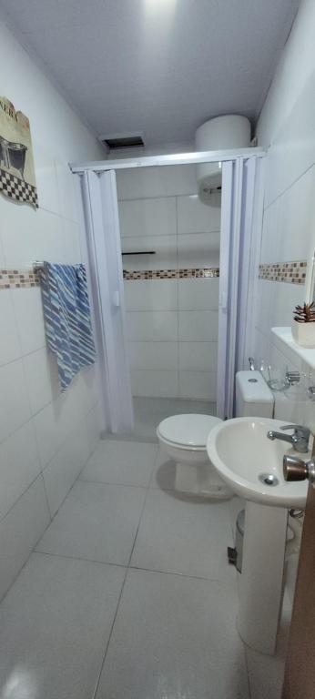 La salle de bains blanche est pourvue de toilettes et d'un lavabo. dans l'établissement Apartamento Romian, à Paysandú