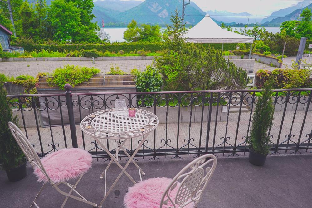 a table with pink cushioned chairs on a balcony at Lake Guest Haus in Därligen