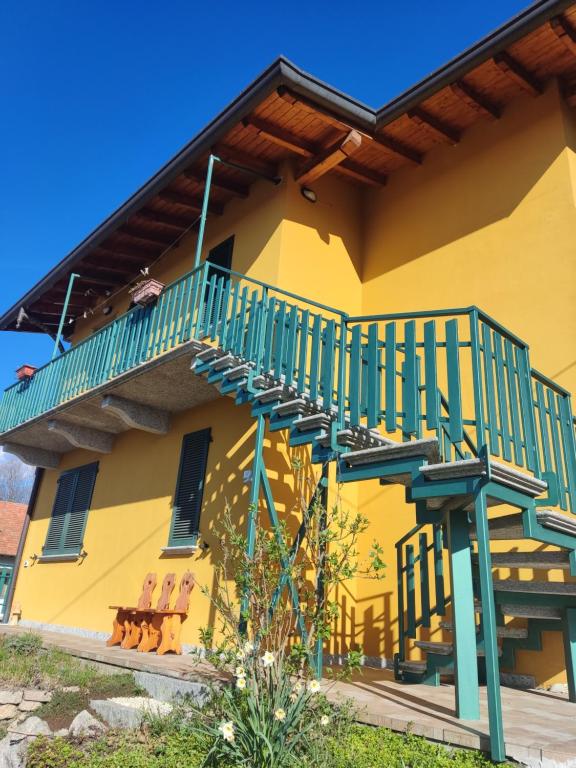 Una casa amarilla con una escalera verde. en Casa Marianne, en Osmate Lentate