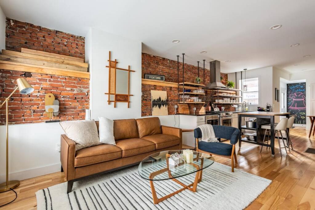 a living room with a couch and a brick wall at Modern Fishtown Townhouse in Philadelphia