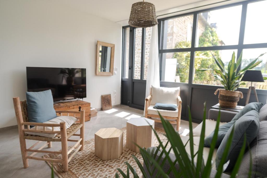 a living room with a couch and chairs and a tv at Gîte avec tennis en Baie du Mont Saint Michel à 15 minutes de la mer in Les Chambres