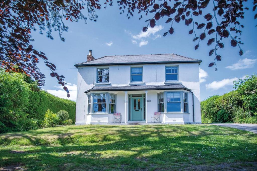 a white house with a blue door on a lawn at Penlan - 3 Bedroom Cottage - Saundersfoot in Saundersfoot