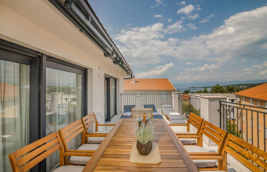 a patio with a wooden table and chairs on a balcony at Apartment Marko by KRALJ TRAVEL in Malinska