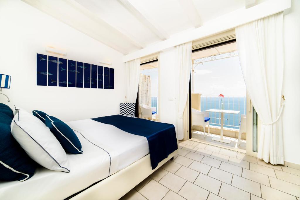 ein weißes Schlafzimmer mit einem Bett und einem großen Fenster in der Unterkunft Residenza Al Pesce D'Oro in Amalfi