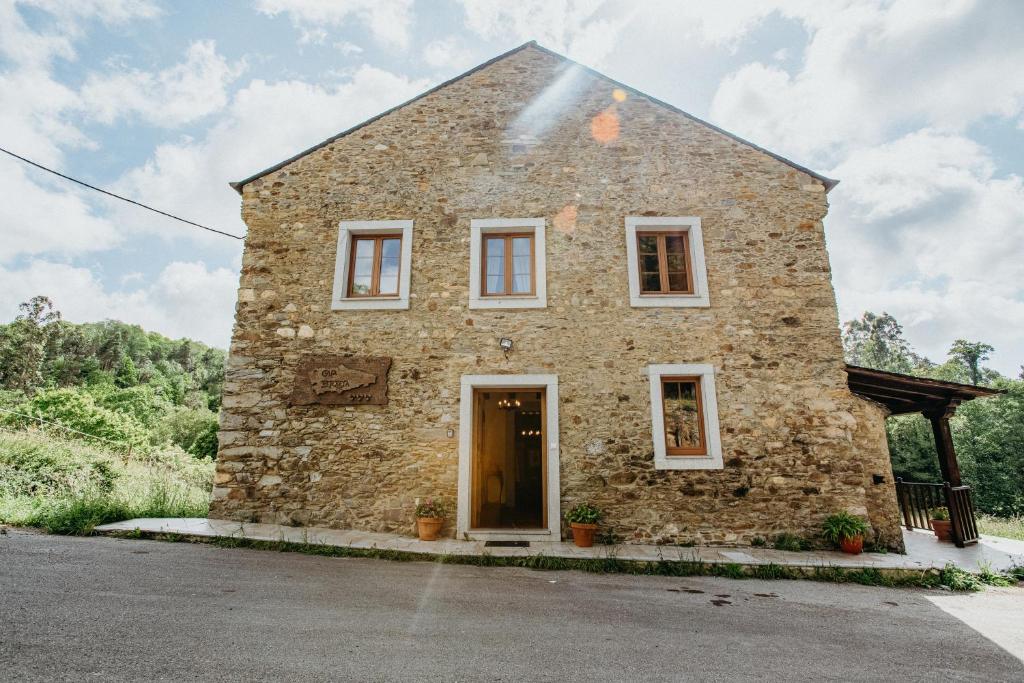 an old stone house with a door on a street at Casa Berbesa in Castropol