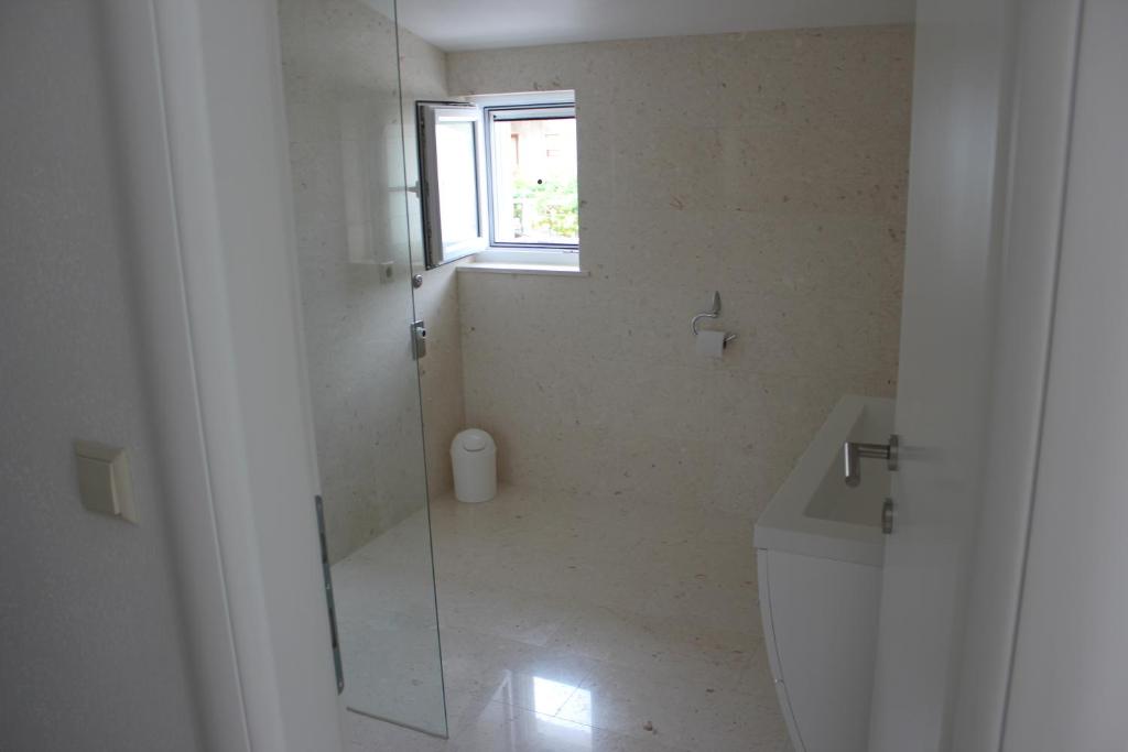 a bathroom with a shower and a toilet and a window at Vila Vito in Trogir