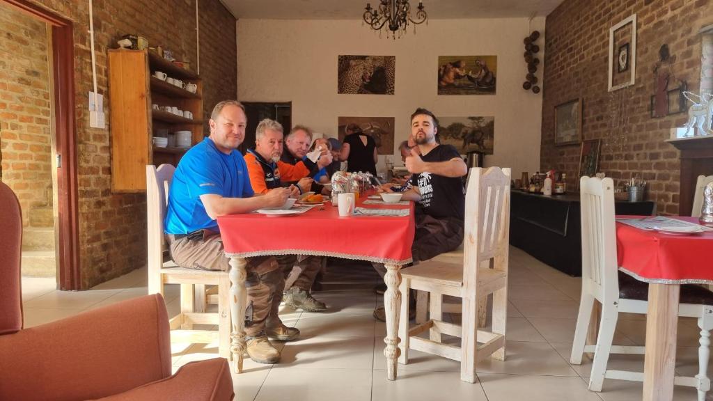grupa mężczyzn siedzących przy stole w restauracji w obiekcie Angel's mist guesthouse w mieście Kaapsehoop