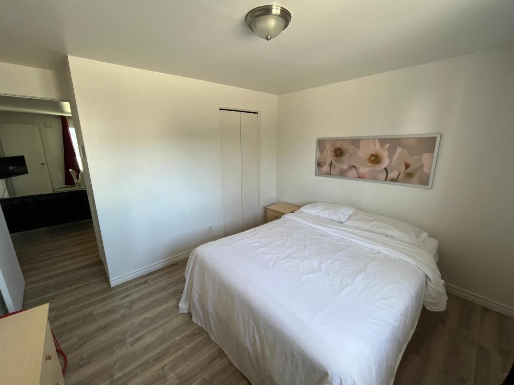 a bedroom with a white bed and a painting on the wall at Auberge Lac-Saint-Jean in Roberval