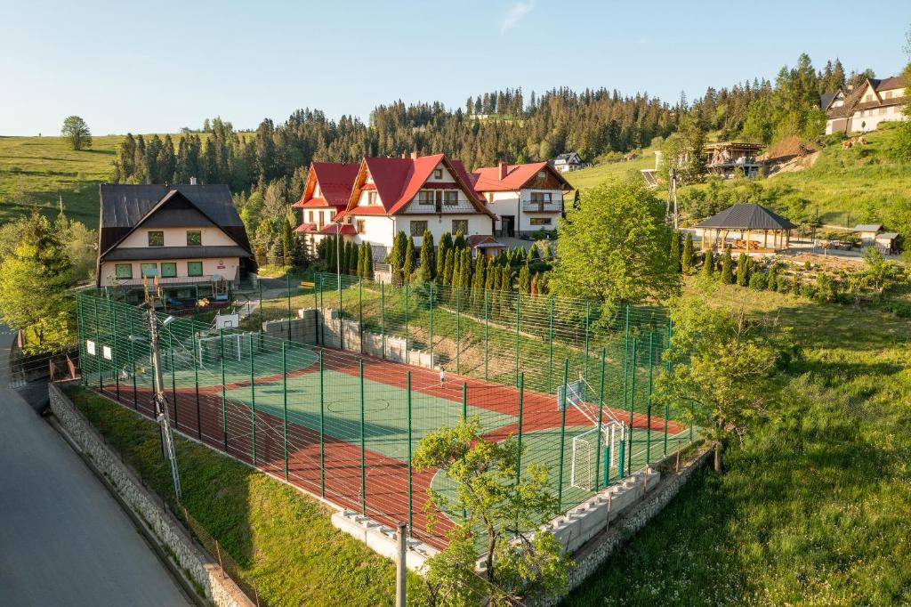 z góry widok na kort tenisowy z domami w obiekcie Dworek na Wzgórzu w Rzepiskach