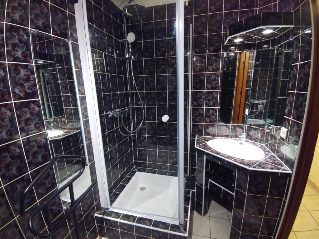 La salle de bains est pourvue de carrelage noir, de deux lavabos et d'une douche. dans l'établissement Gîte Lion d'Or, à Le Bonhomme