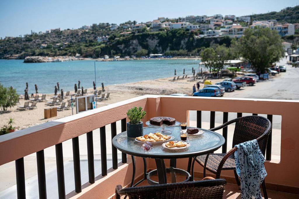 una mesa con comida en un balcón con vistas a la playa en Elena Apartments, en Almyrida
