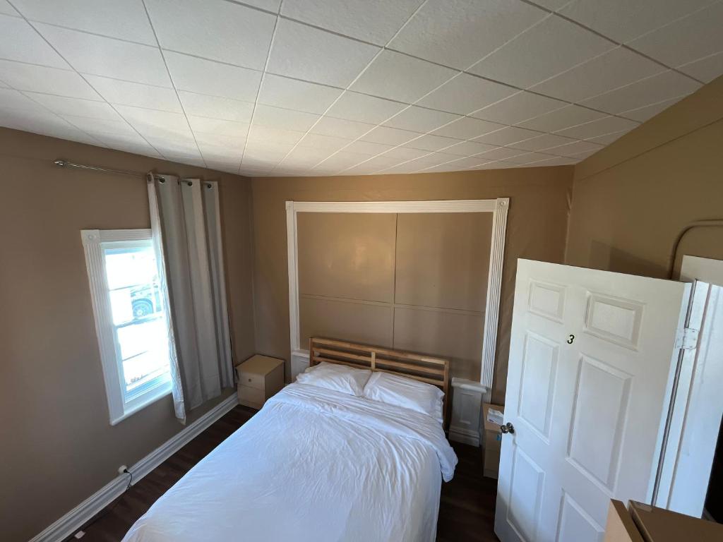 a bedroom with a white bed and a window at Auberge Lac-Saint-Jean in Roberval