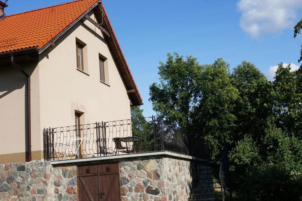 Casa blanca con balcón en una pared de piedra en Bociani domek u Barbary en Giże