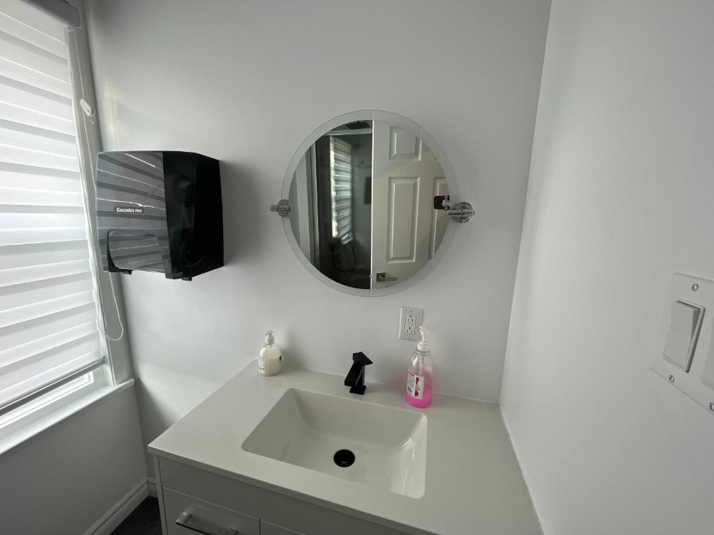 a white bathroom with a sink and a mirror at Auberge Lac-Saint-Jean in Roberval