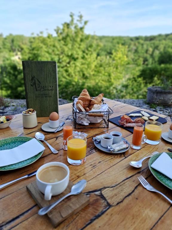 a wooden table with breakfast foods and drinks on it at Domaine du Châtelard in Dirac