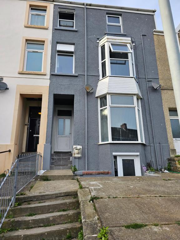 a grey house with a staircase in front of it at Lovely Apartment in Swansea in Swansea