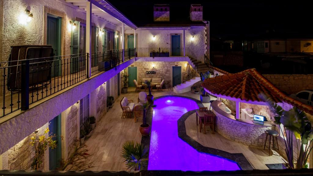 una piscina al aire libre por la noche con luces moradas en Avlu Alaçatı Boutique Hotel en Alacati