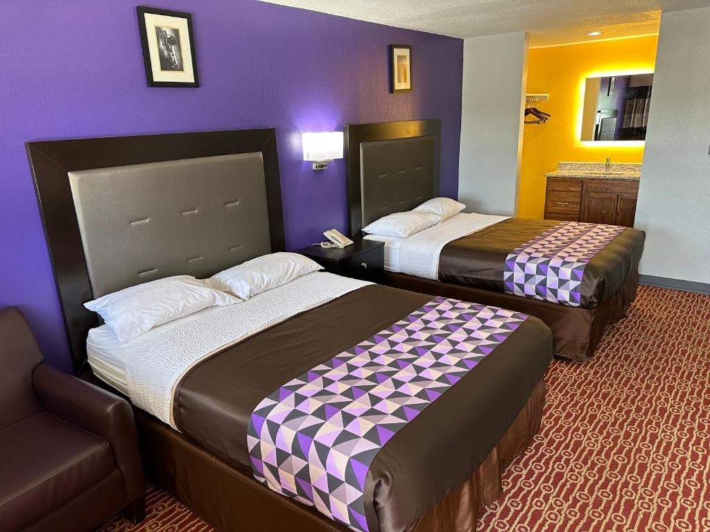 two beds in a hotel room with purple walls at Magnolia Motel Donaldsonville in Donaldsonville