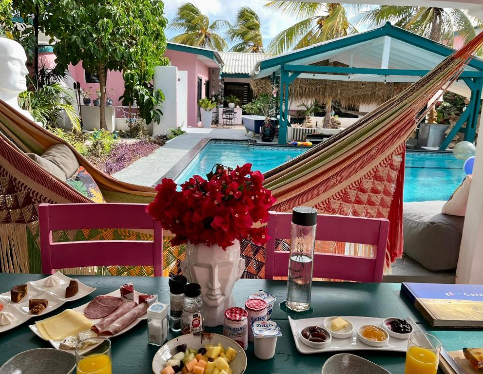 a table with food and flowers next to a pool at THUISHAVEN boutique mini-resort - fantastic garden and large pool - adults only in Willemstad
