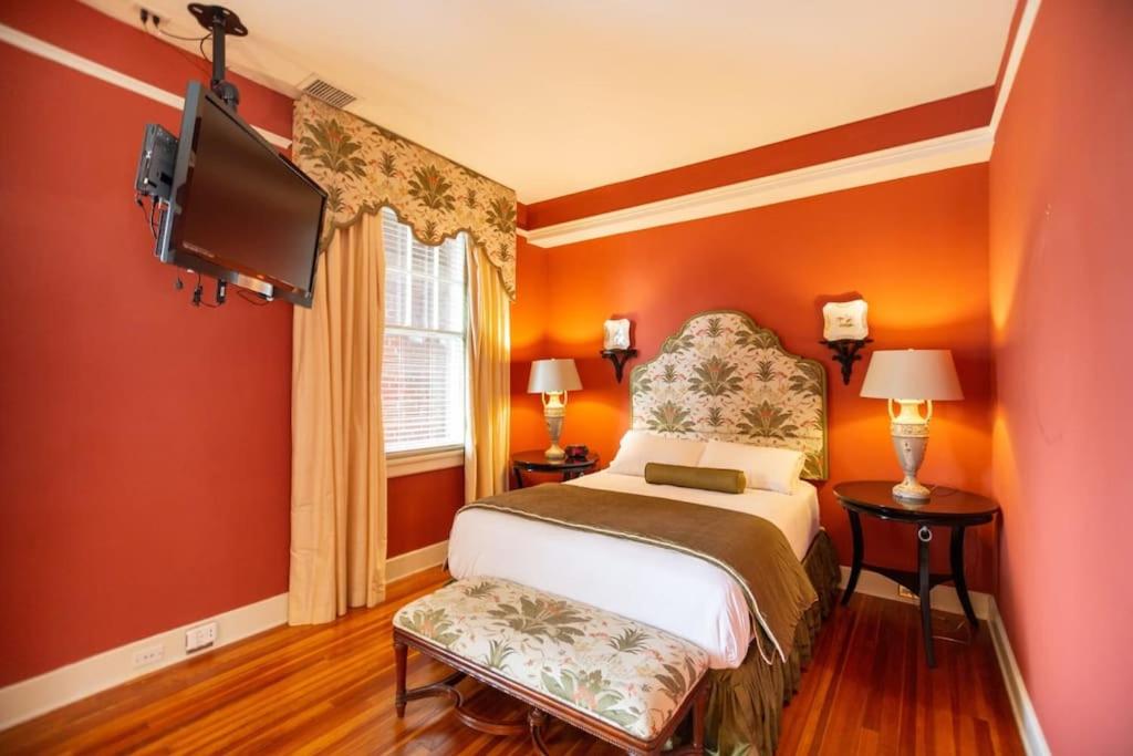 a bedroom with orange walls and a bed and a tv at Charming Durham Studio Steps Away from Duke in Durham
