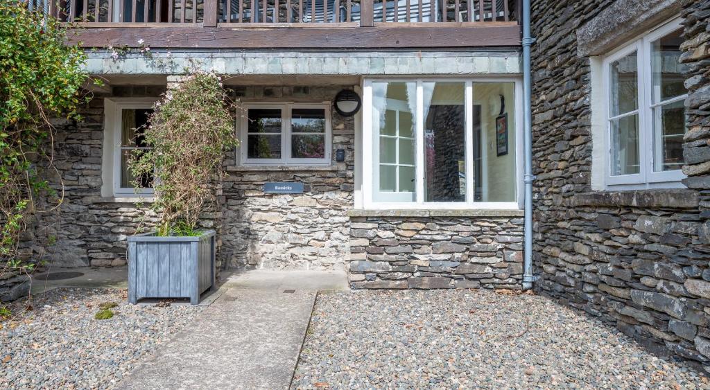 a stone house with two windows and a door at Bassicks in Rusland