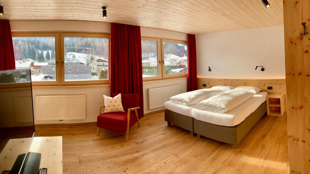 a bedroom with a large bed and a red chair at Residence Emmy in San Candido