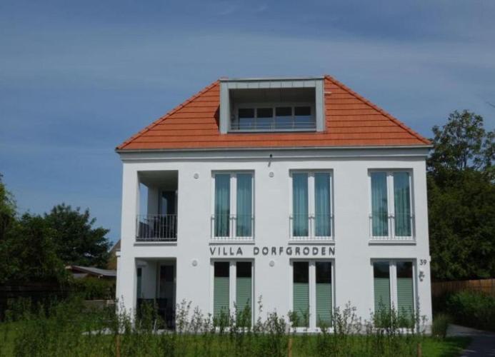 ein weißes Gebäude mit orangefarbenem Dach in der Unterkunft Strandlust - Anspruchsvolle Ferienwohnung in Wangerooge