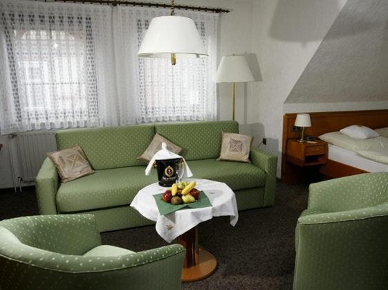 un soggiorno con divano verde e letto di Hotel Restaurant Pempel a Großalmerode
