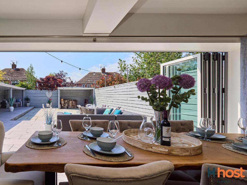 una mesa de madera con un jarrón de flores púrpuras. en Host Liverpool - Greasby Luxury Home, Near Golf & Beach en Greasby