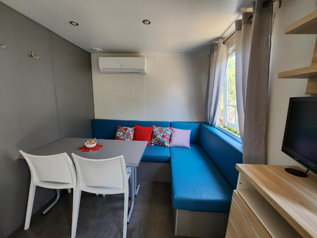 a small room with a blue couch and a table and chairs at Le clos de lignac in Cieux