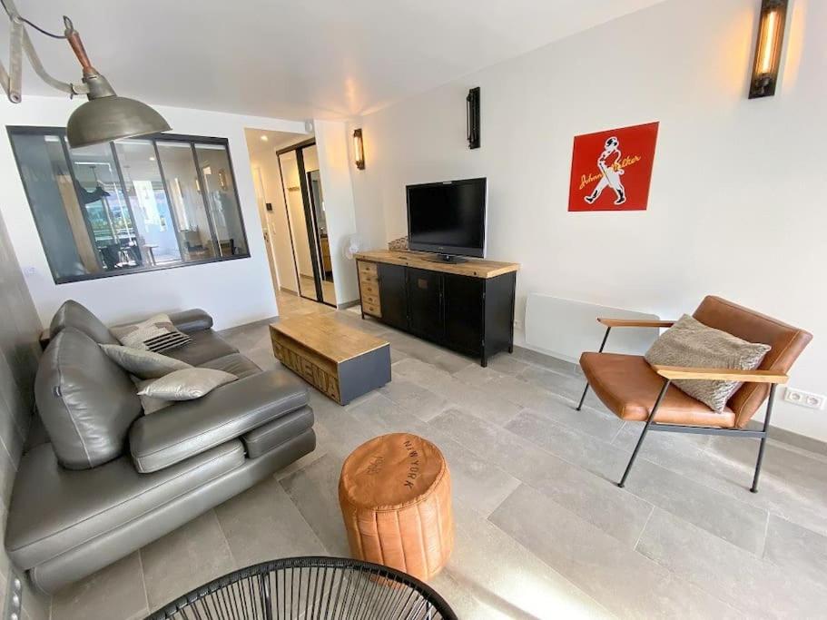 un salon avec un canapé en cuir et une télévision dans l'établissement Appart 113, Port Ambonne au village naturiste, au Cap d'Agde