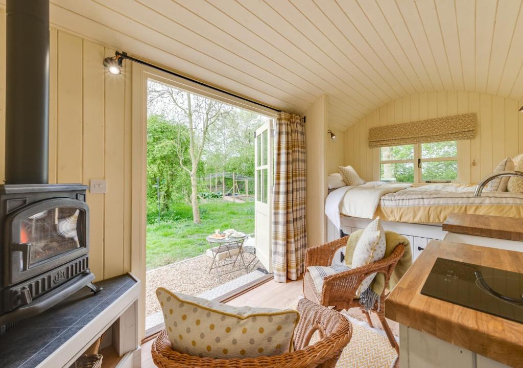 a room with a fireplace and a bedroom with two beds at The Orchards Retreat Shepherds Hut in Saint James