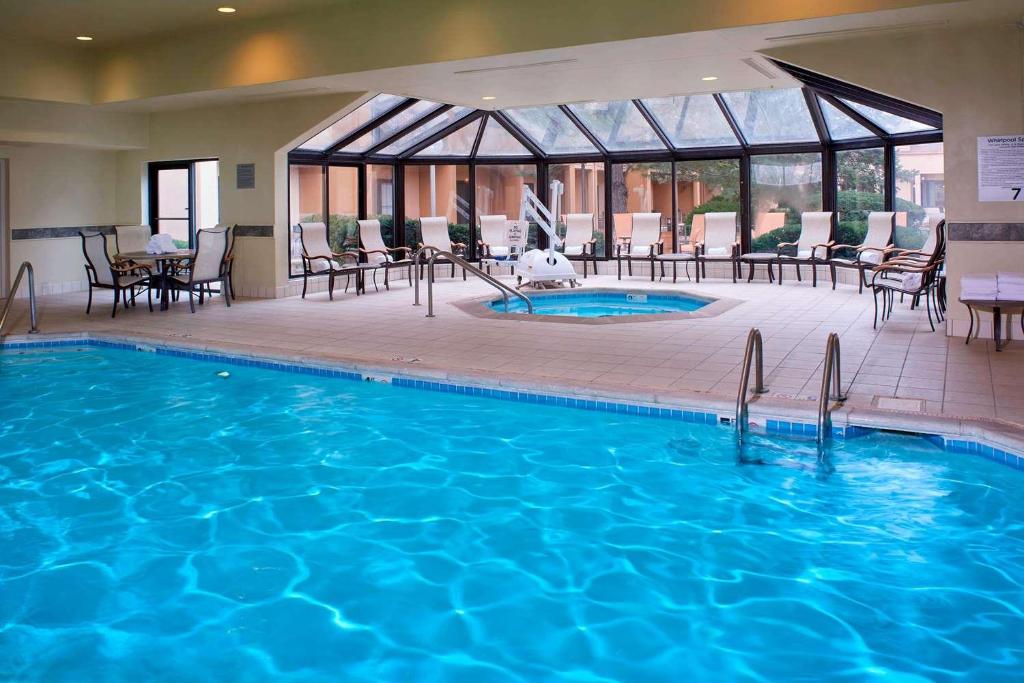 a pool in a hotel with chairs and tables at Sonesta Select Kansas City Airport Tiffany Springs in Kansas City