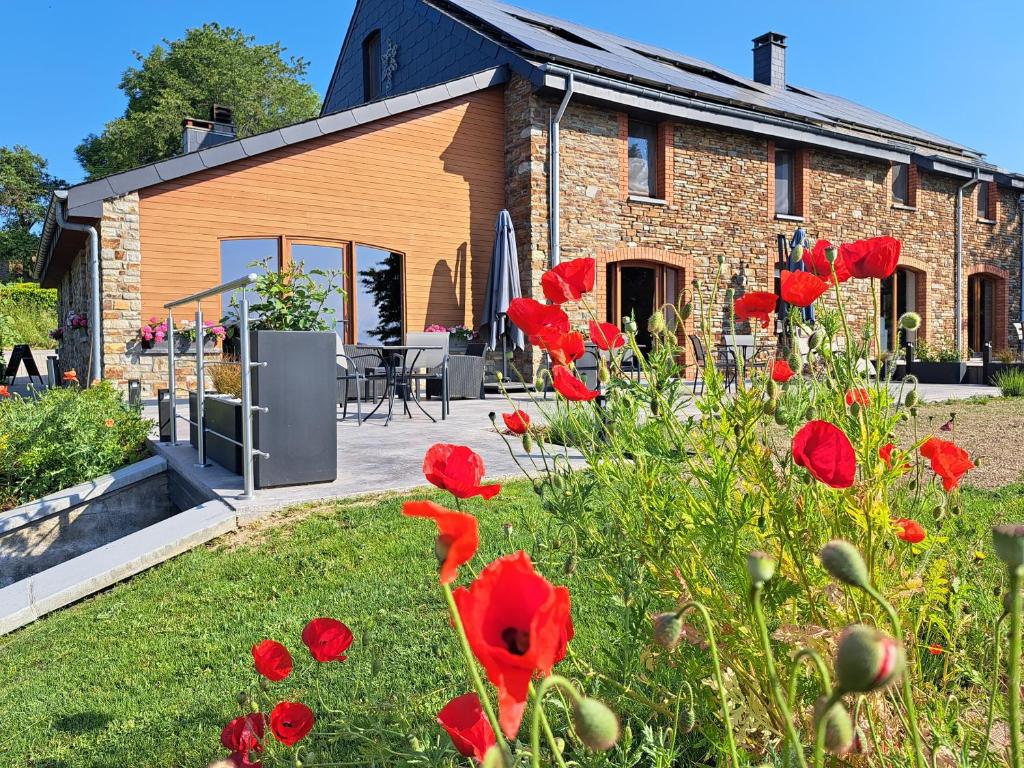 Chanteloup, Maison d'hotes - Halleux في Halleux: منزل أمامه زهور حمراء