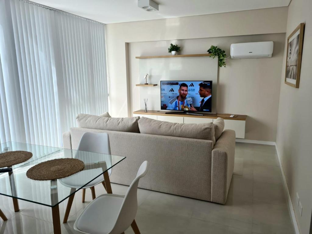 a living room with a couch and a tv on a wall at Departamento premium para 3 personas in Puerto Madryn